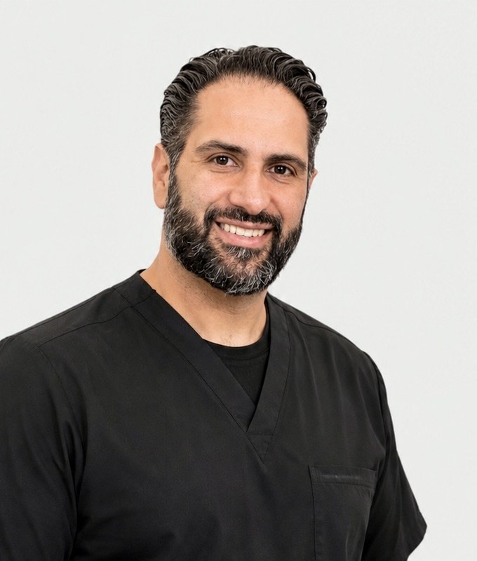 Dr. Payam Asadi, DMD, smiling in black scrubs