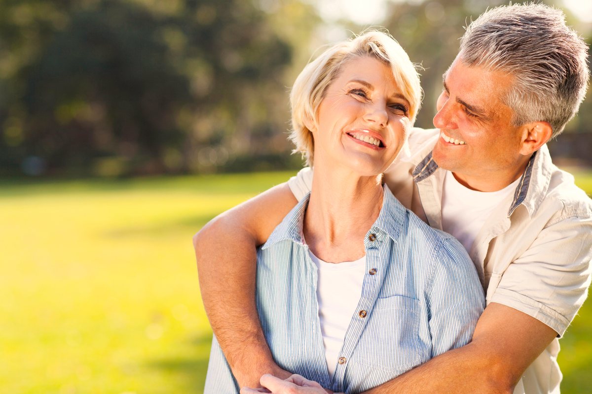 A happy couple hugging and laughing outdoors on a sunny day